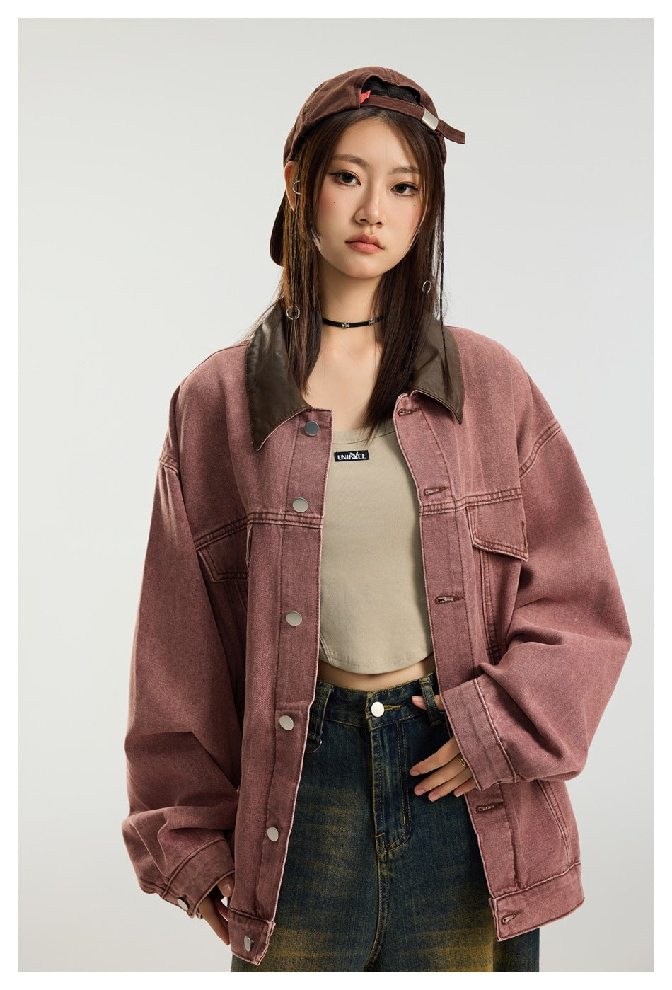 A model wears an oversized dusty rose jacket with a dark brown collar, metal snaps, and flap pockets.