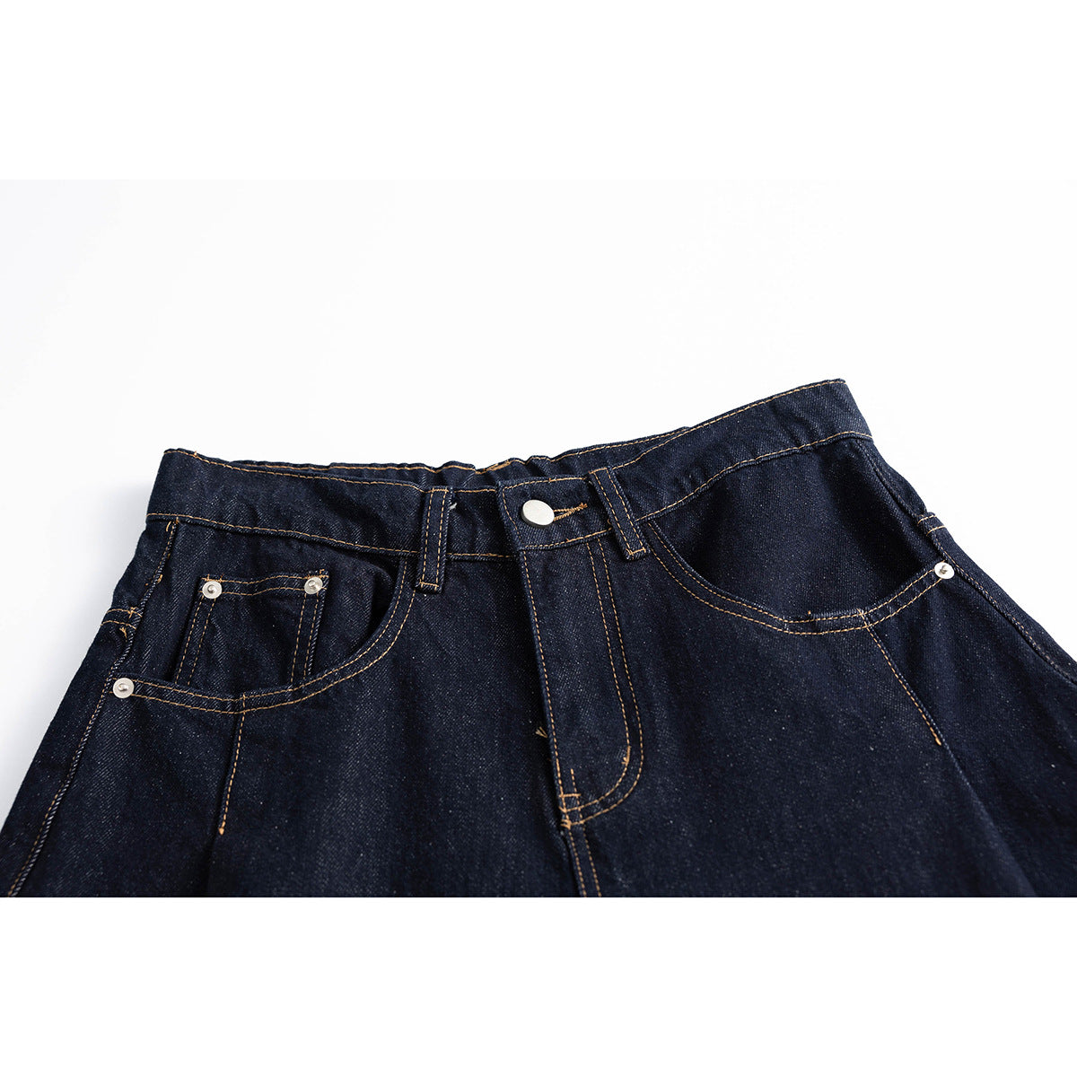 Close view of dark indigo jeans front waist with button, belt loops, coin pocket and contrast stitching.