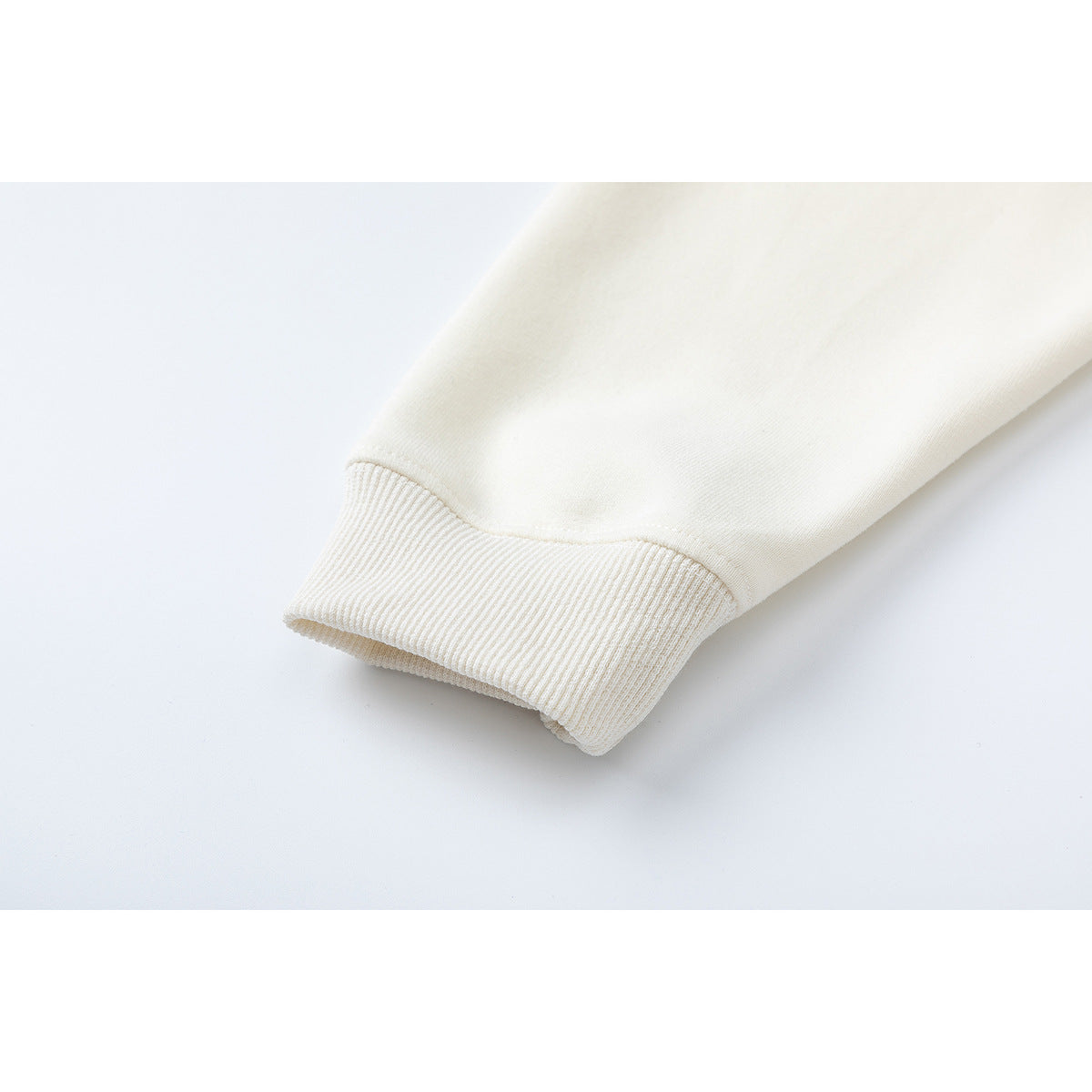 Close-up of a cream sweatshirt sleeve ending in a ribbed cuff.