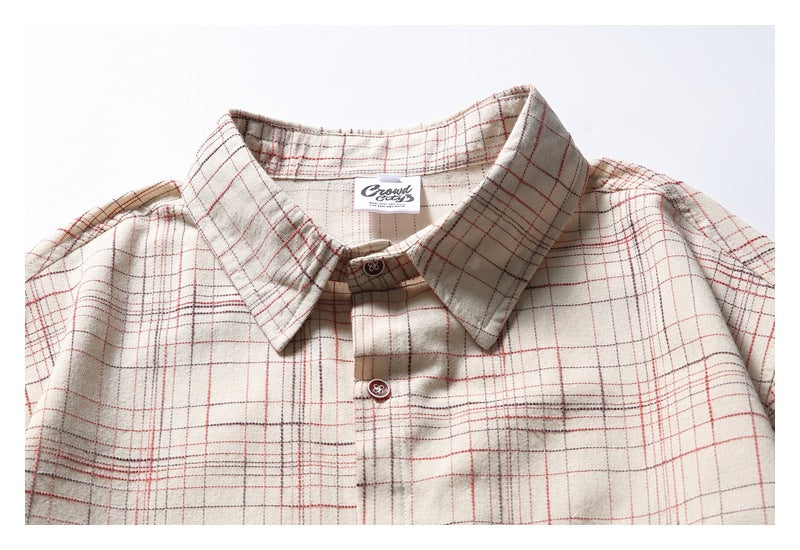 Cropped front view of an off-white plaid button-up shirt showing its collar, buttons, and one chest pocket.