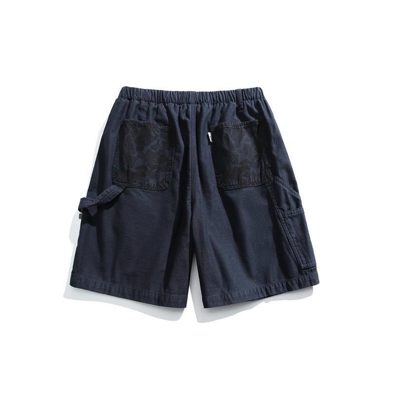 Navy shorts shown flat with an elastic waistband, two patterned back pockets, and a cargo pocket at the side.
