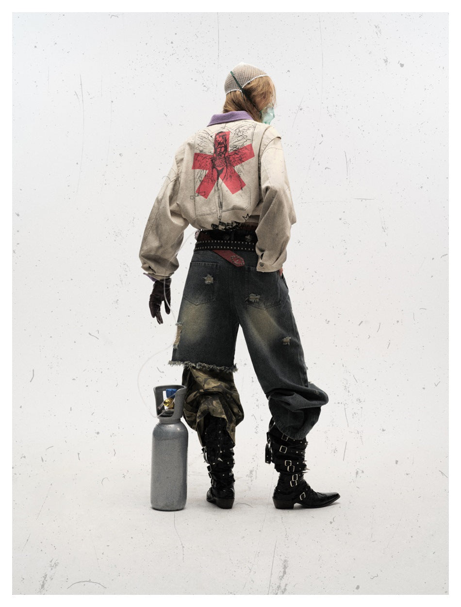 Rear view of a model wearing a beige jacket with a large red-and-black back graphic, dark jeans, and boots.
