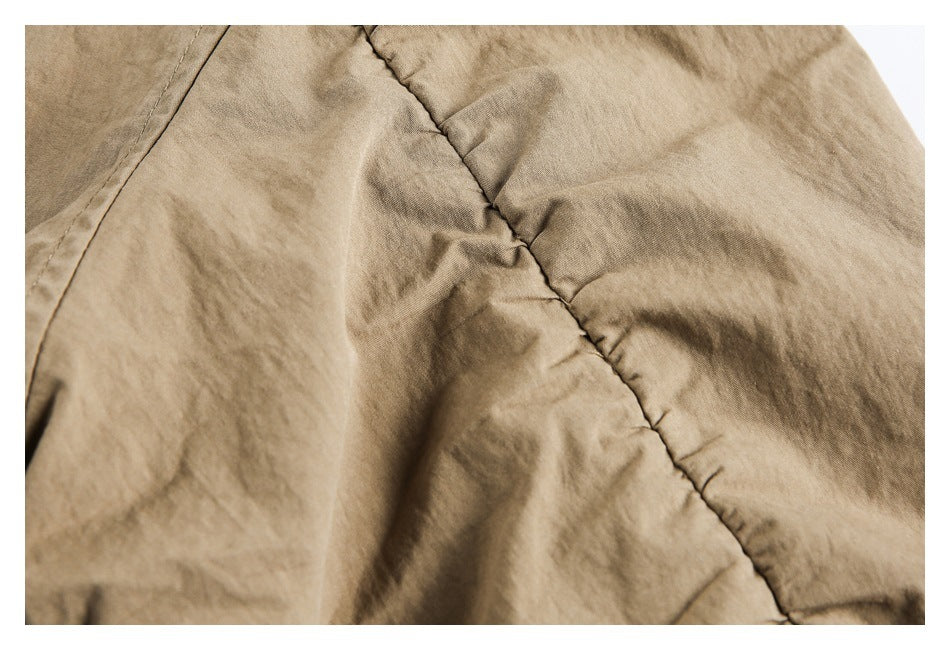 Close-up of tan garment fabric and a diagonal stitched seam.