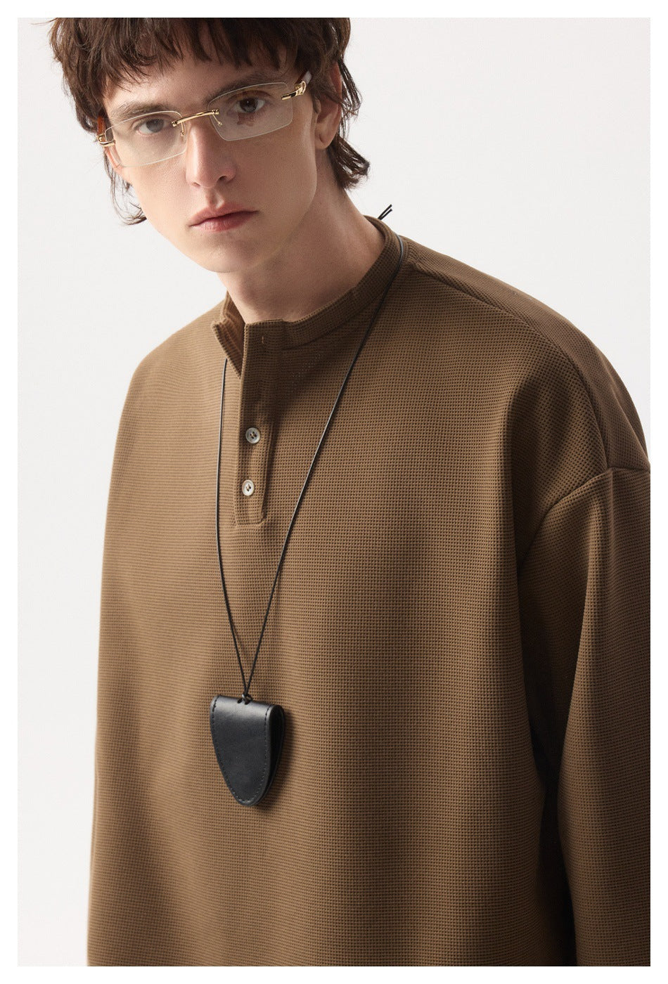Close-up of a brown textured henley top showing its short button placket and fabric surface.