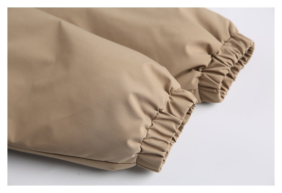 Close-up of a tan garment with gathered elastic edging along two fabric sections.