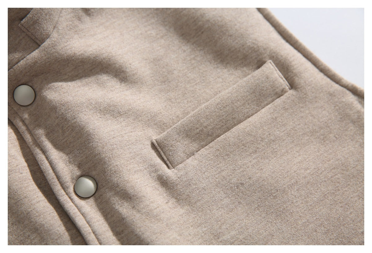Close-up of a beige coat front with metal snap buttons and a horizontal welt pocket.