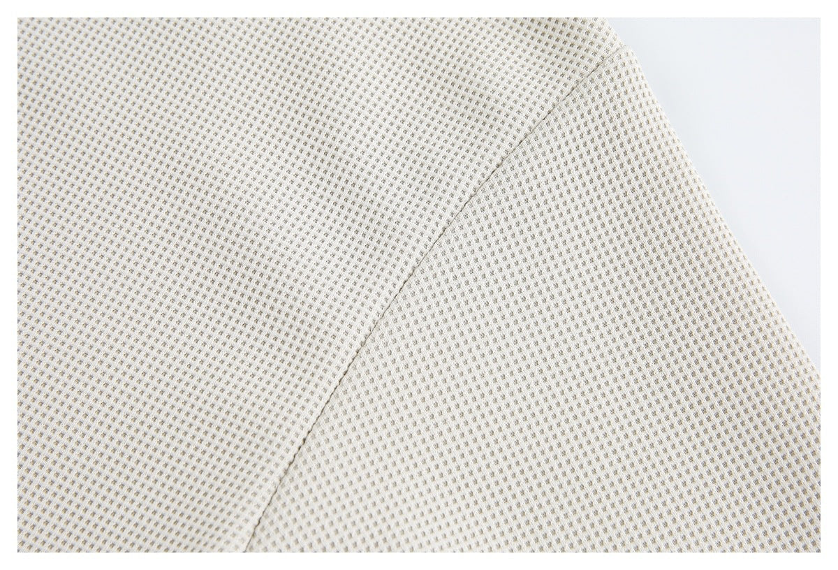 Close-up of off-white textured fabric with a fine repeating pattern and a diagonal seam.