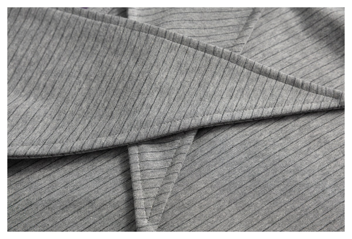 Close-up of gray fabric with fine dark pinstripes folded to show its surface and drape.