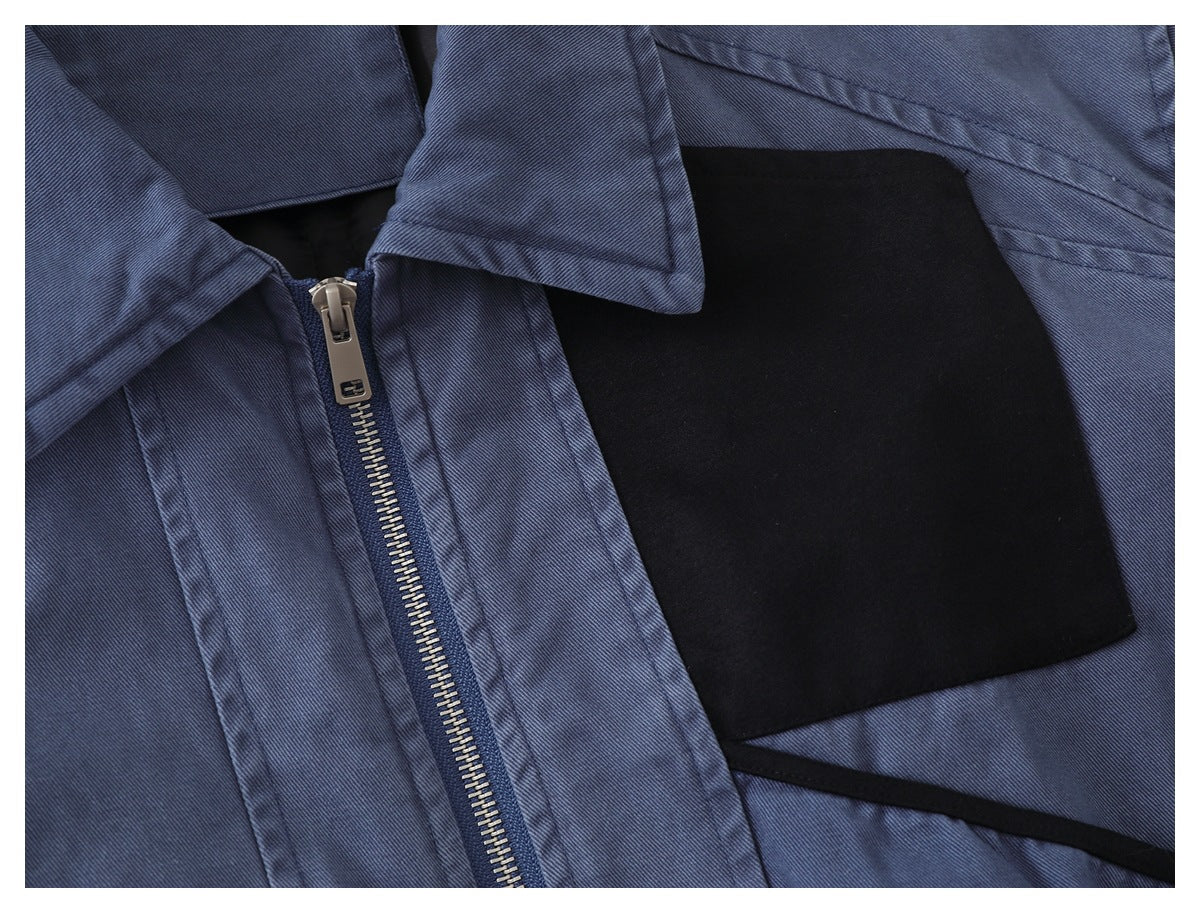 Blue-gray jacket close-up showing a metal zipper, collar edge, and black interior panel.