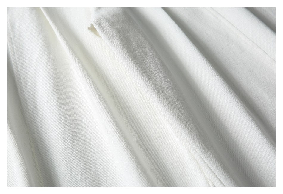 Close-up of softly folded white fabric with a fine diagonal weave.