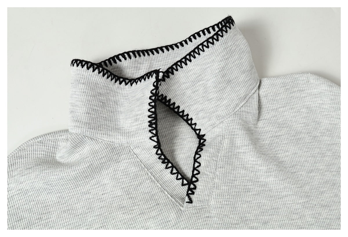 Close-up of a light gray ribbed collar with black zigzag stitching along its edges.