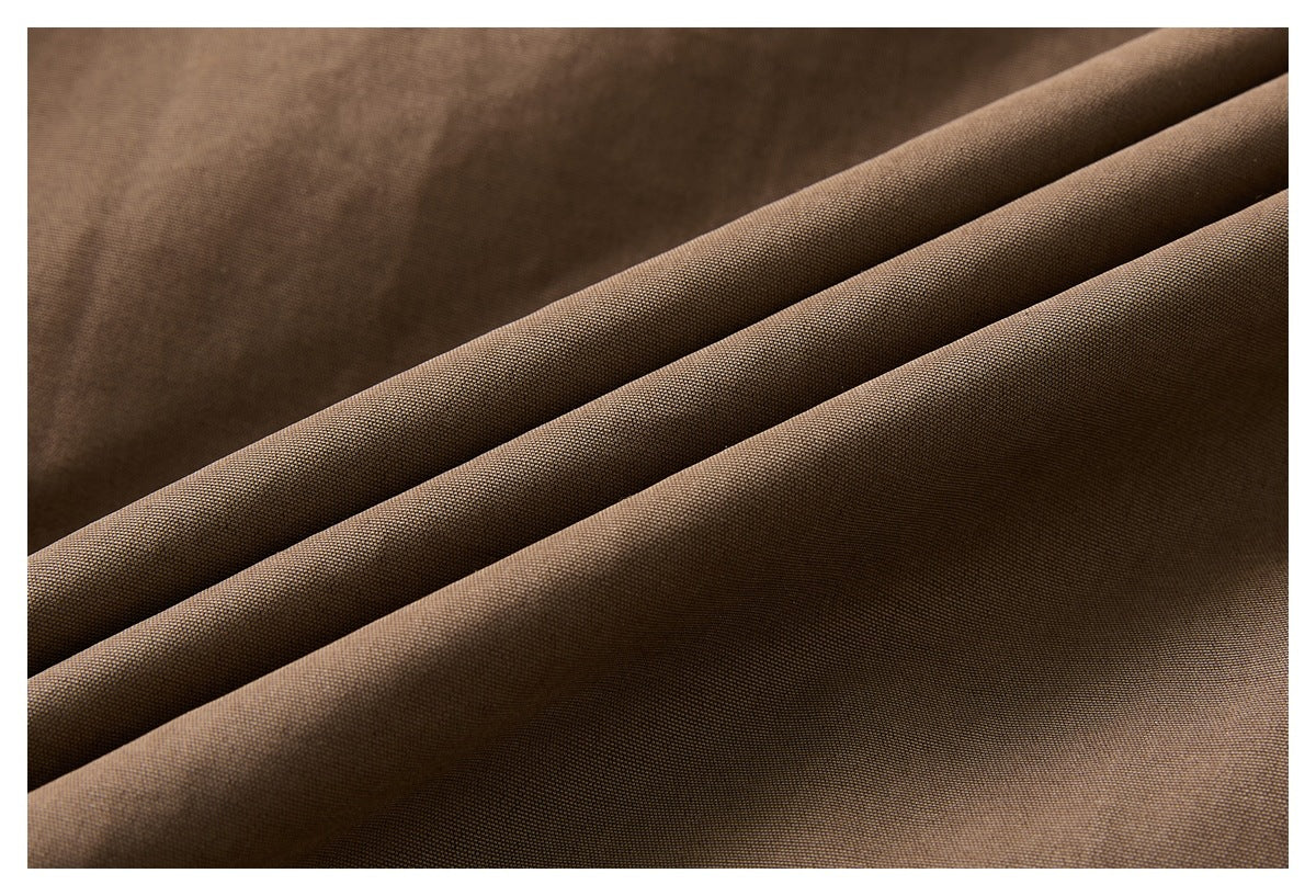 Close-up of brown fabric draped in folds, showing its fine woven texture.