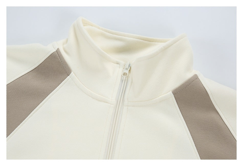 Close-up of an ivory zip-up jacket collar, zipper, and taupe shoulder panels.