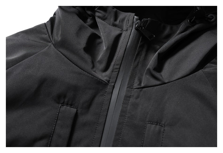 Close-up of a black jacket’s front zipper, hood toggles, and upper pocket openings.