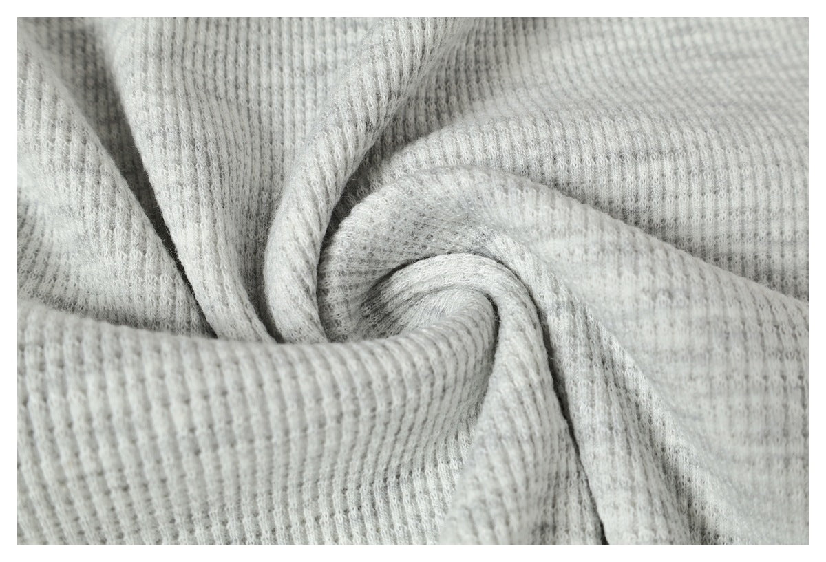 Macro view of light gray ribbed knit fabric gathered into soft folds.