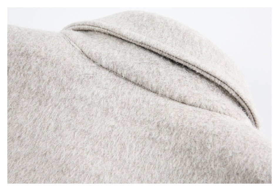 Close-up of the pale beige coat's overlapping collar or lapel and fuzzy surface.