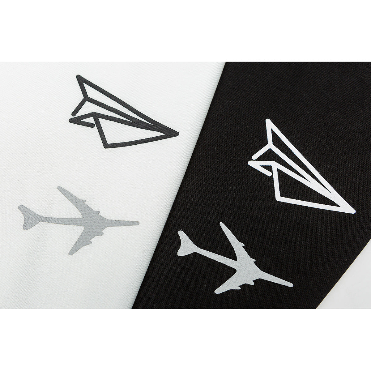 Close-up of paper-airplane and airplane graphics printed on white and black T-shirt fabric.