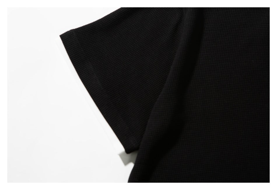 Close-up of the black shirt's short sleeve and textured fabric.