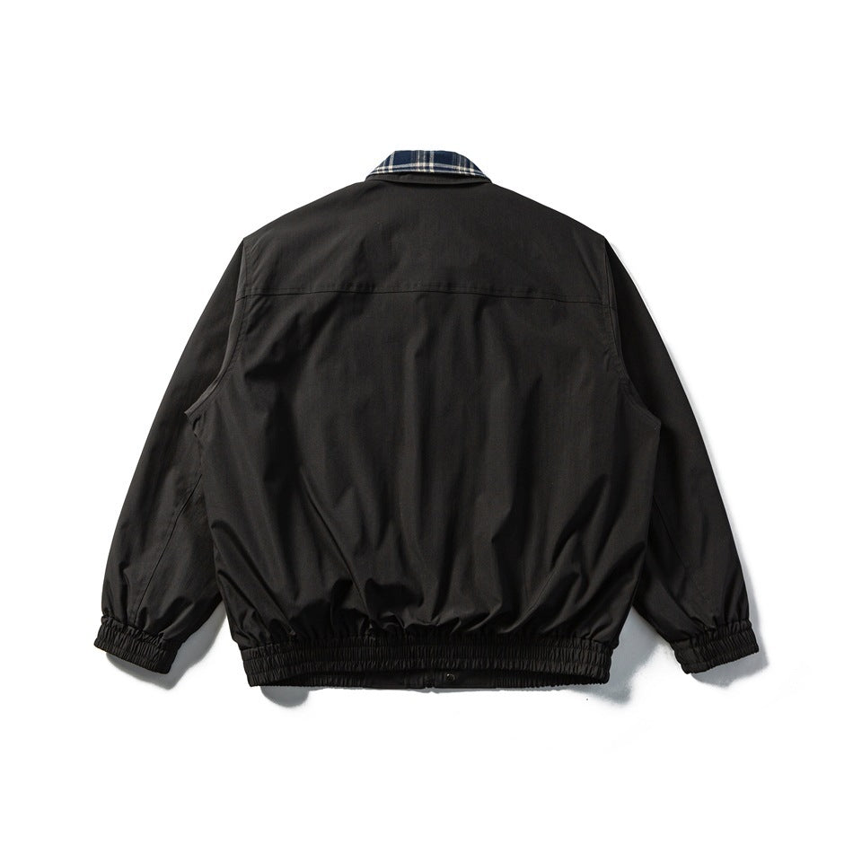 Back view of a black jacket with elasticated cuffs and waistband and a plaid collar.