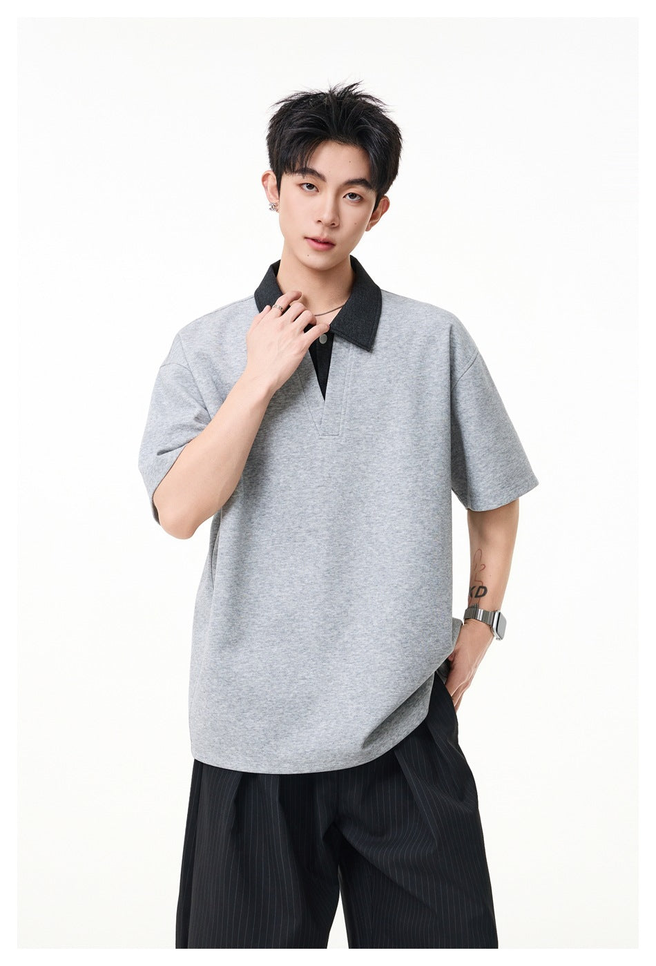 Closer view of a model wearing a gray polo with a contrasting dark collar and short button placket.