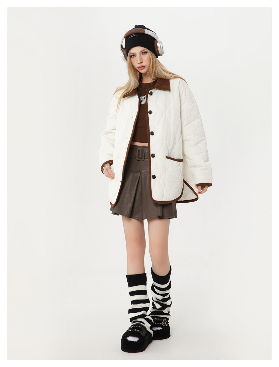Model wearing a white quilted jacket with brown trim and collar, paired with a dark brown skirt.