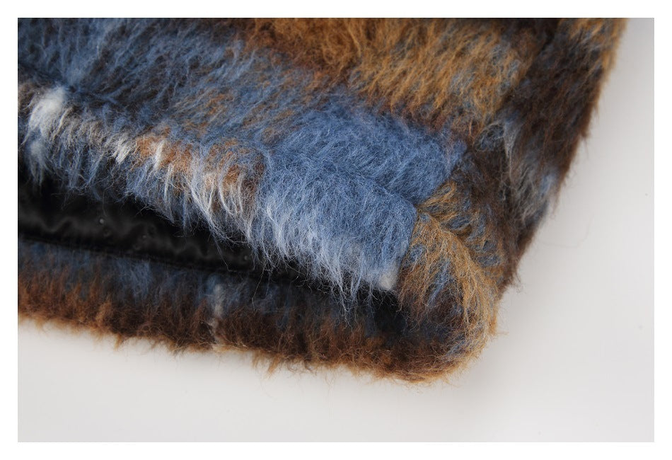 Close-up of a brown, blue, and gray fuzzy plaid garment edge with black lining.