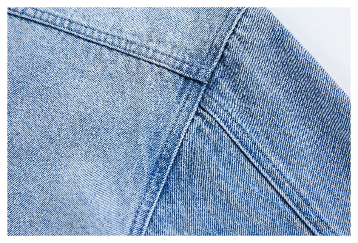 Close-up of light blue denim panels with intersecting double-stitched seams.