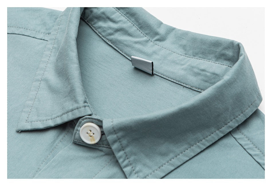 Close-up of a pale blue shirt collar, white button, and inner neckline.