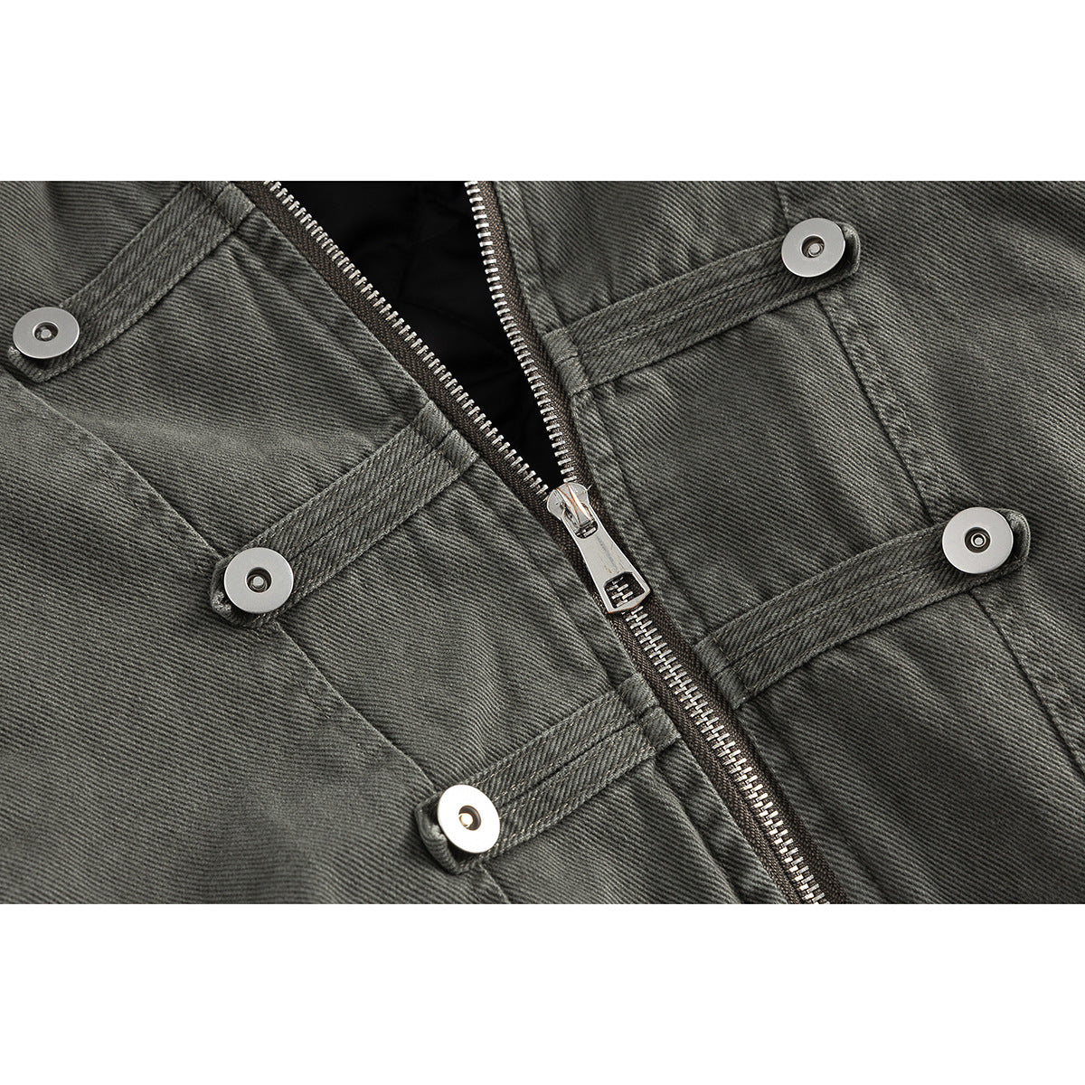 Close-up of a charcoal gray jacket front with a metal zipper and several buttoned horizontal straps.