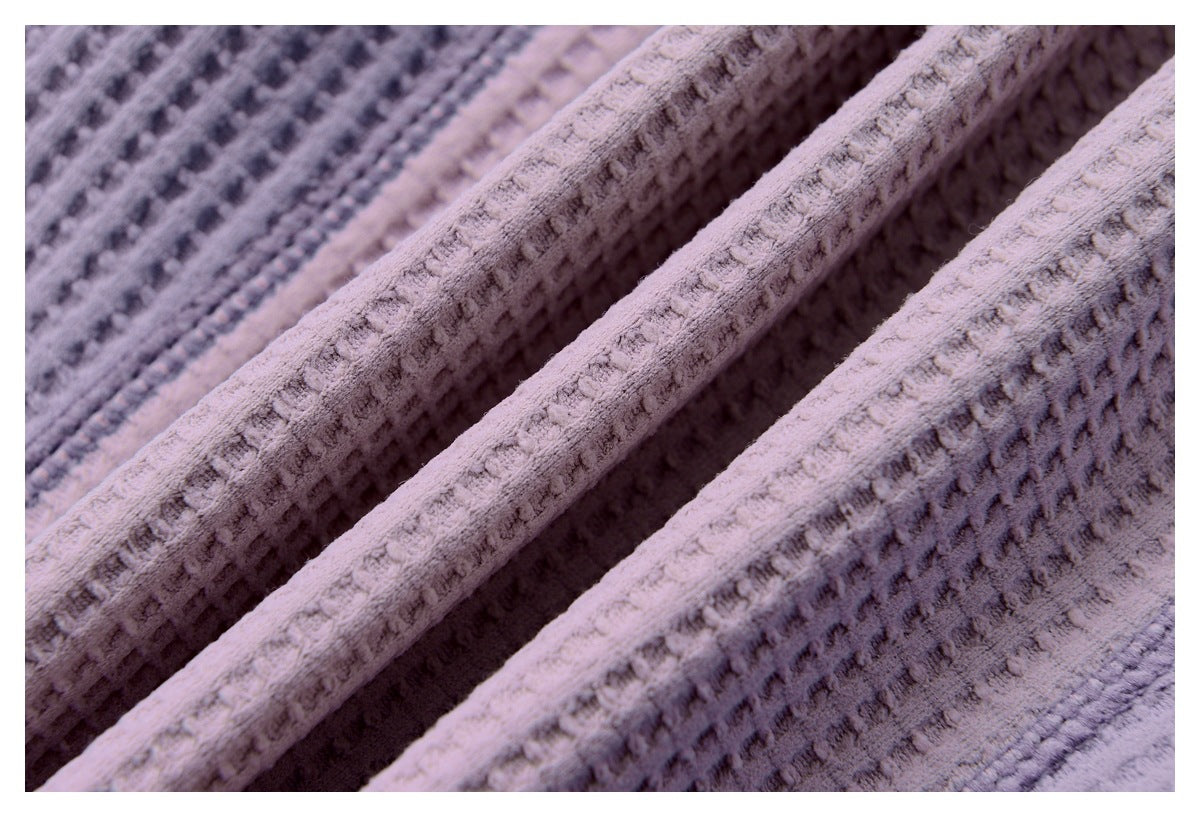 Close-up of pale pink and lavender textured fabric arranged in soft folds.