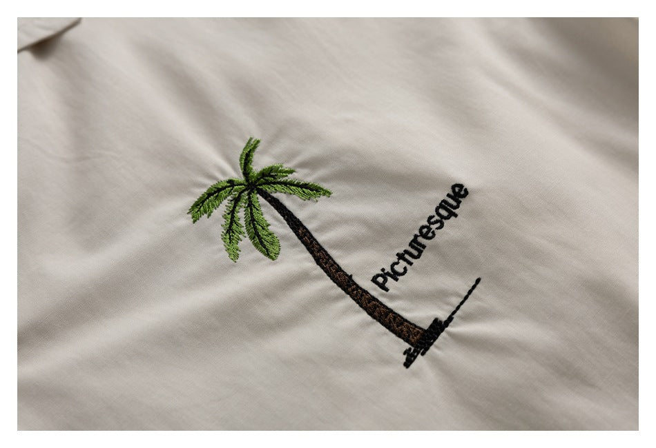 Close-up of a palm tree and the word “Picturesque” embroidered on ivory shirt fabric.
