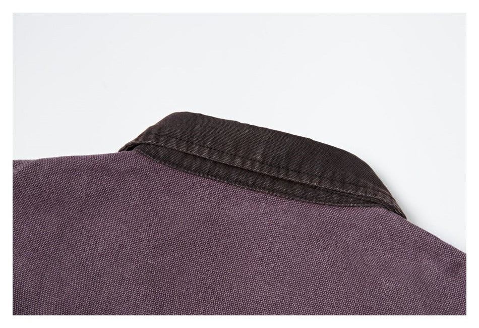 Close-up of a dark collar against the muted purple fabric of a garment.