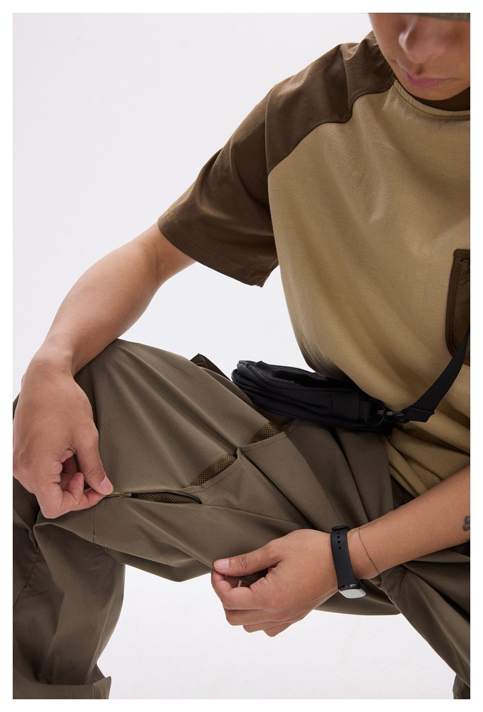 Close-up of taupe cargo pants showing a mesh-lined zip vent, worn with a tan-and-brown shirt.