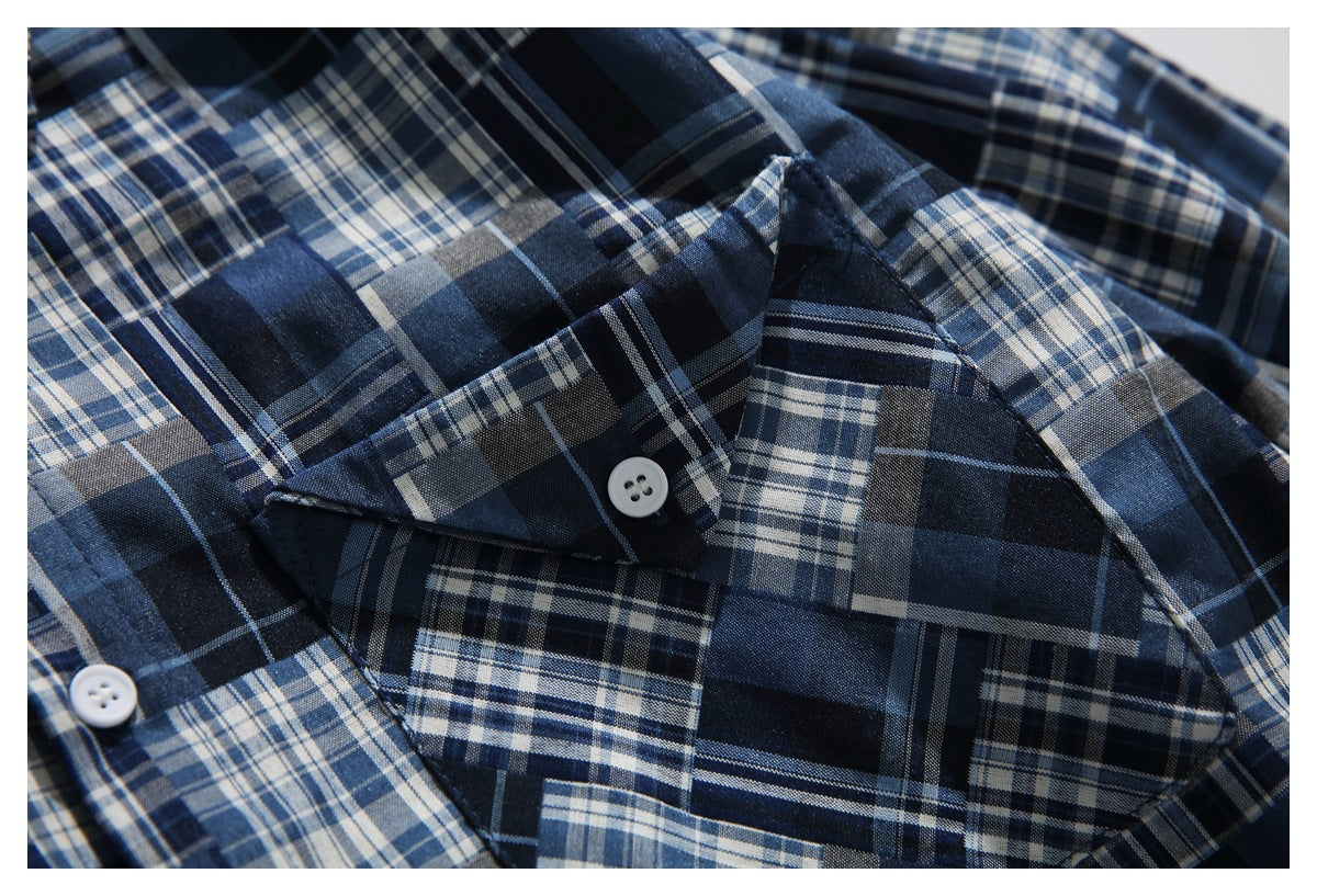 Close-up of a navy, blue, gray, and white plaid shirt collar and chest pocket with white buttons.