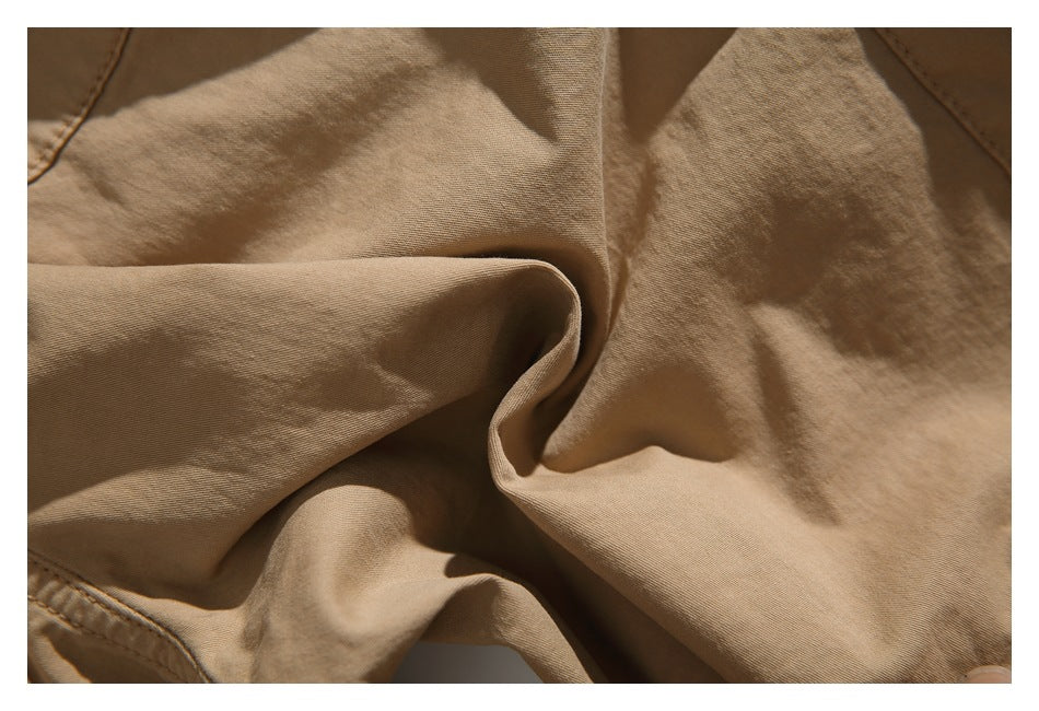 Close-up of the tan shorts fabric folded to show its surface and stitching.