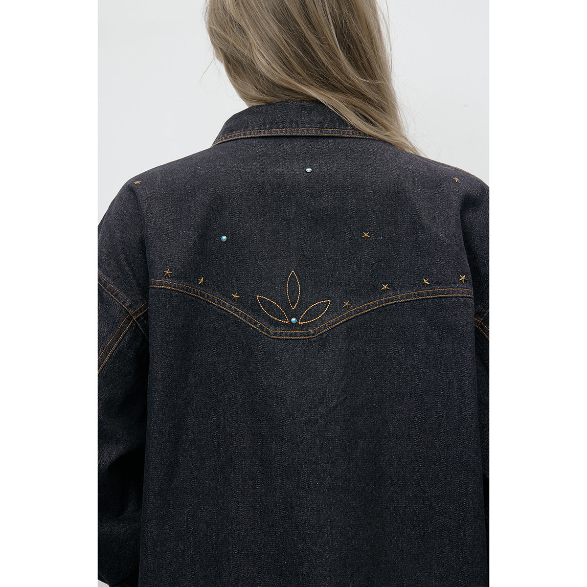 Close-up of the jacket’s back, showing tan stitched floral and star details with small blue accents.