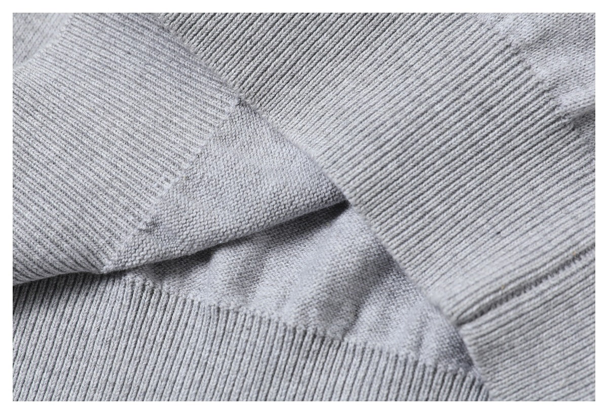 Extreme close-up of the gray sweater's ribbed knit trim and joining seam.