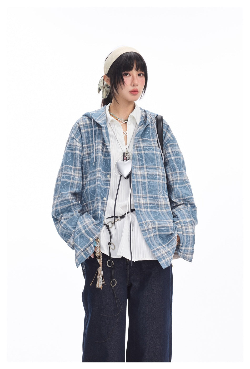 Front view of a model wearing an oversized blue-and-white plaid hooded shirt jacket over a white blouse and dark jeans.