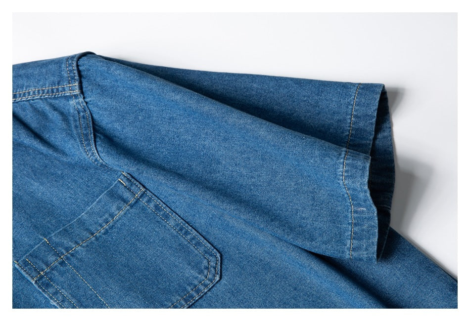 Close-up of a blue denim shirt sleeve and chest pocket with tan contrast stitching.