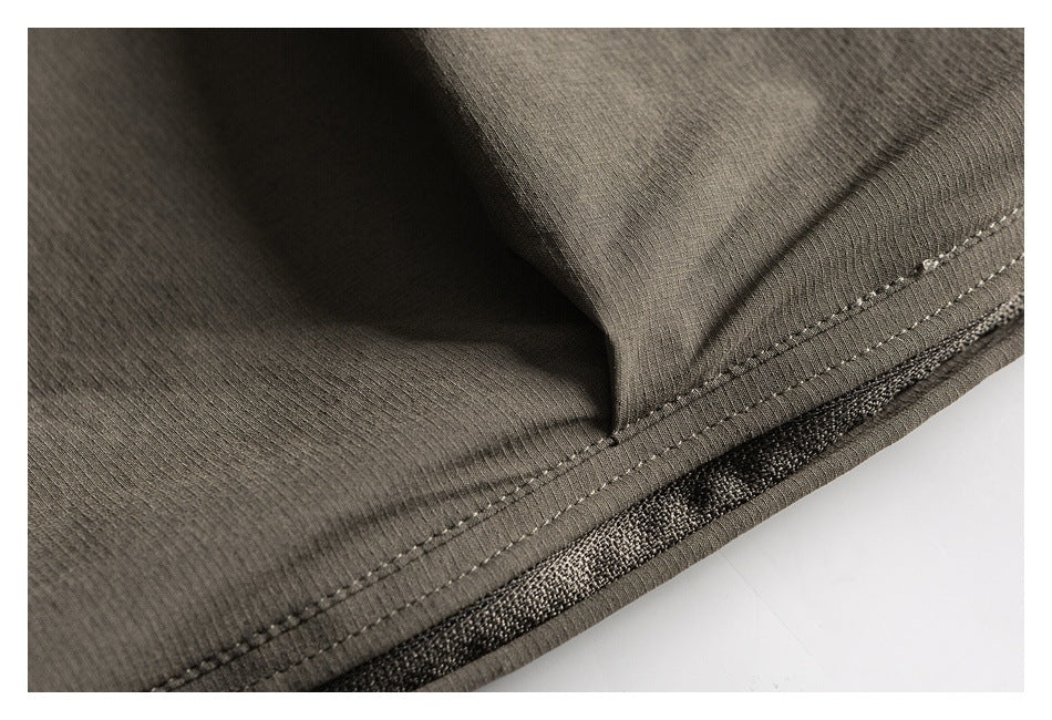 Close-up of an olive-gray garment hem with parallel stitching and textured mesh visible beneath the edge.