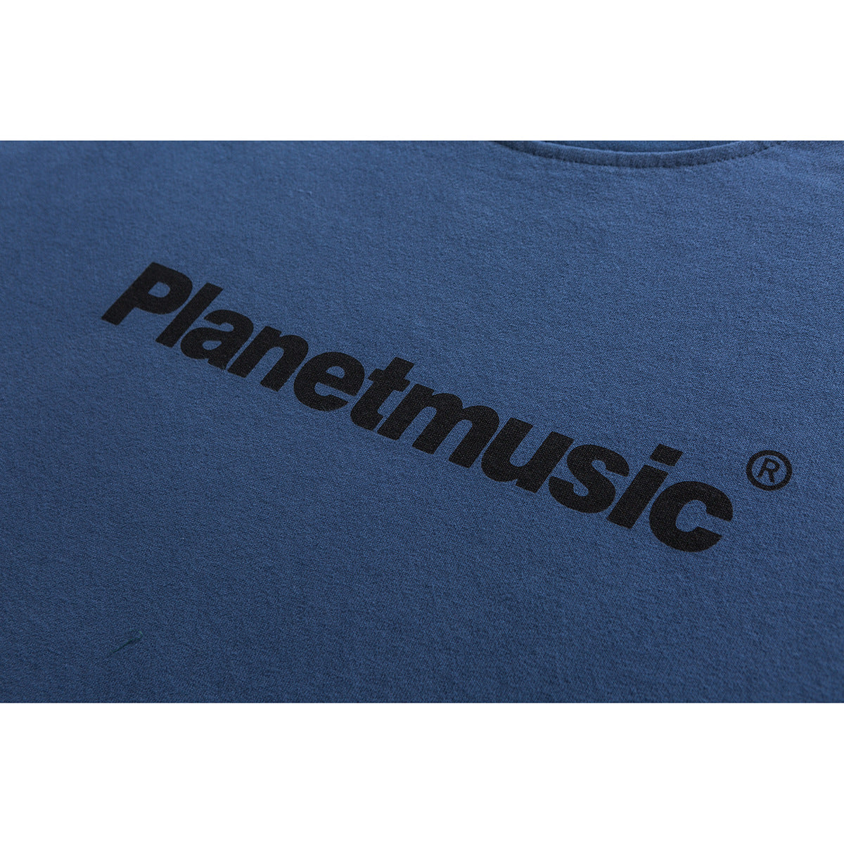 Close-up of black Planetmusic lettering printed on a blue T-shirt.