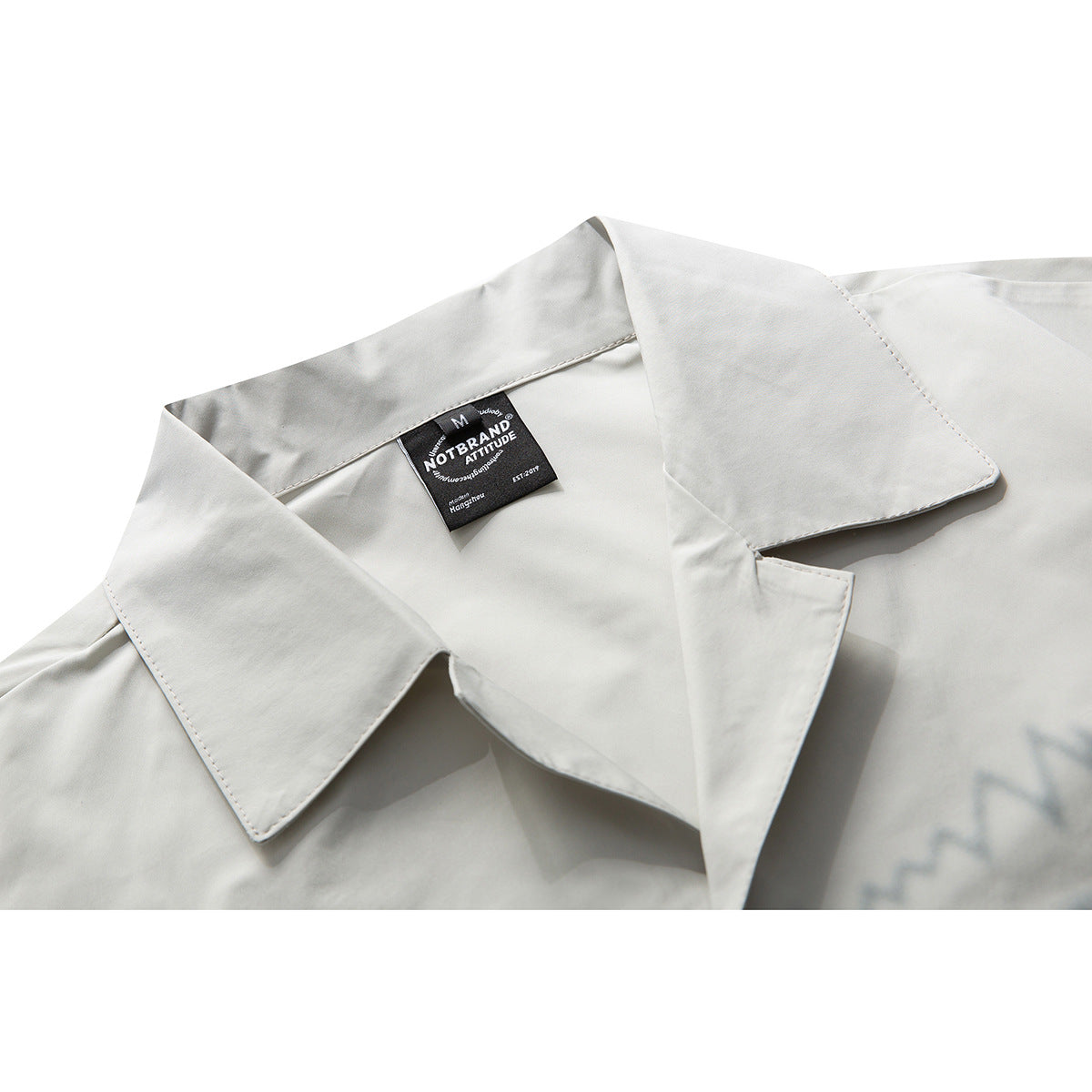 Close-up of an off-white shirt's wide pointed collar and black neck label.