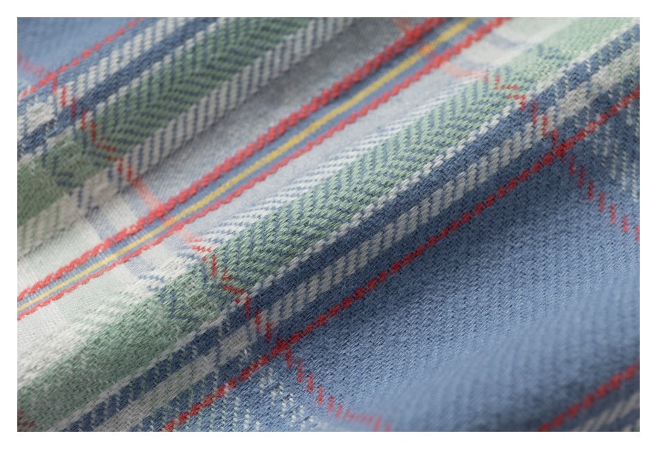 Macro view of the blue, green, white, and red plaid fabric texture.