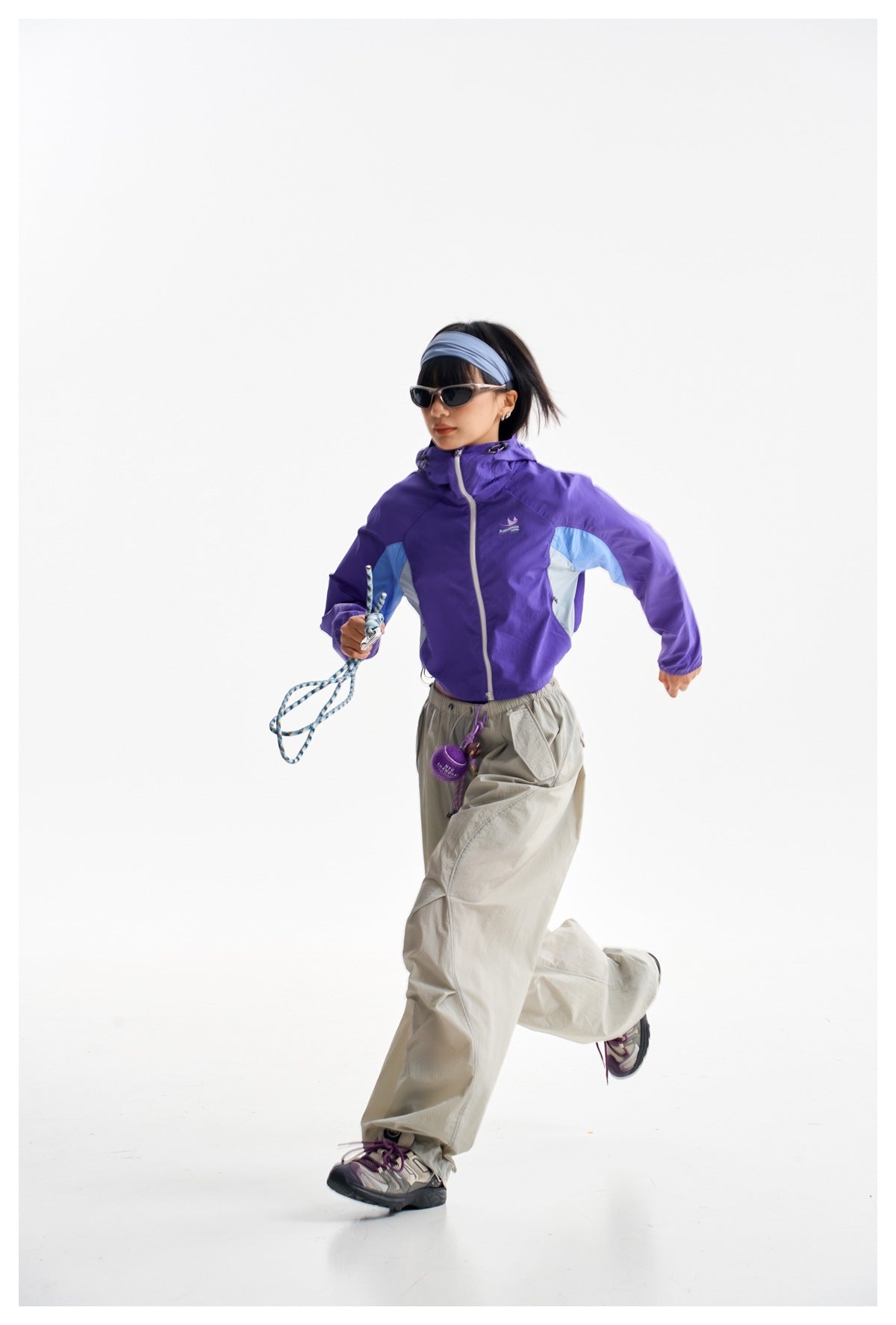 Model wearing a purple hooded windbreaker with light-blue and white panels, zipped front, and elastic cuffs.