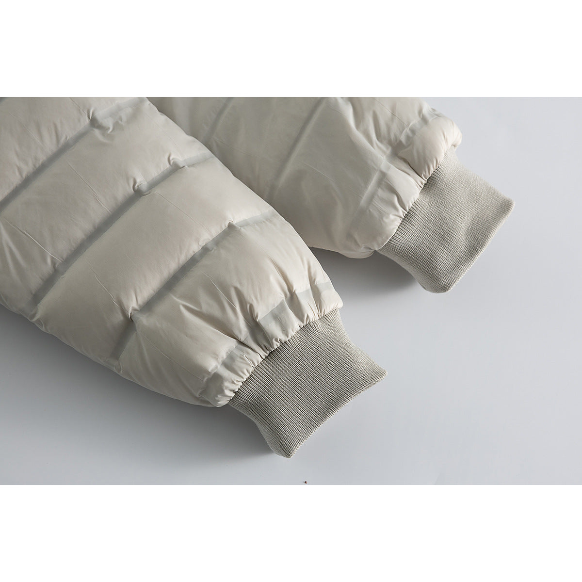 Close-up of a light gray jacket's quilted sleeves and ribbed knit cuffs.