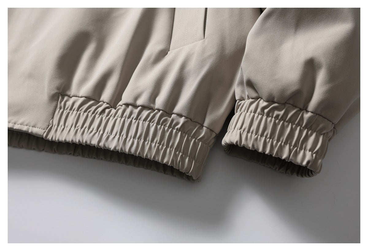 Close-up of taupe trousers showing two gathered elastic ankle hems.