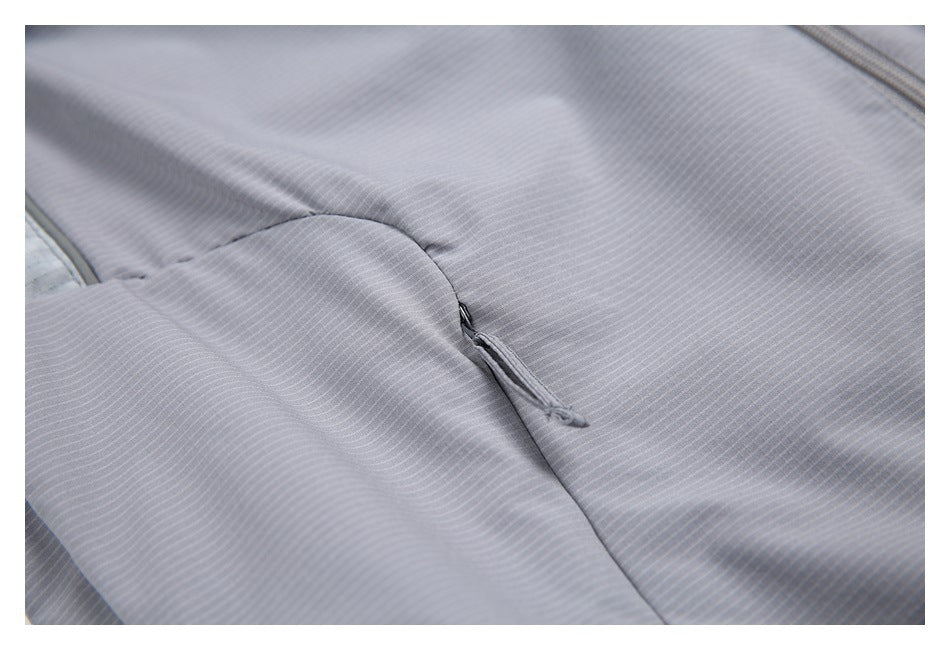 Close-up of a small zipper on a gray garment panel with fine pinstripes.