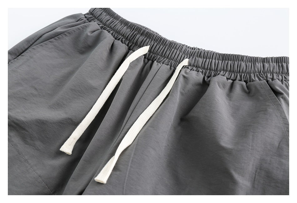 Close-up of gray bottoms with a gathered elastic waistband and long white drawstrings.
