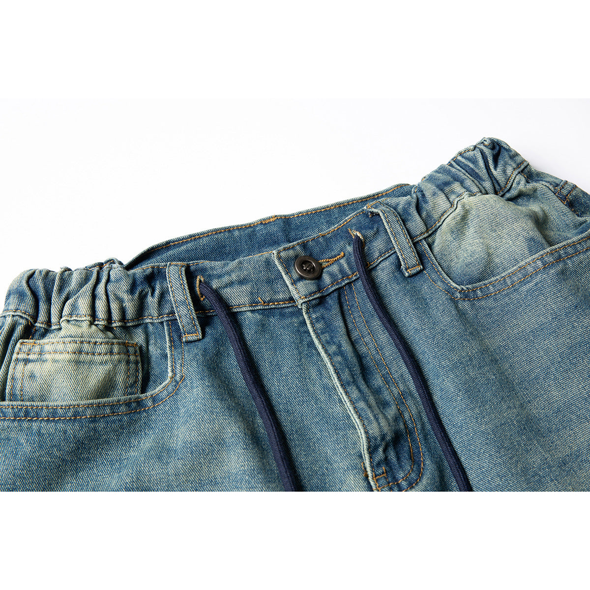 Close-up of blue denim trousers with an elasticized waistband, dark drawcords, button closure, belt loops and front pocket.