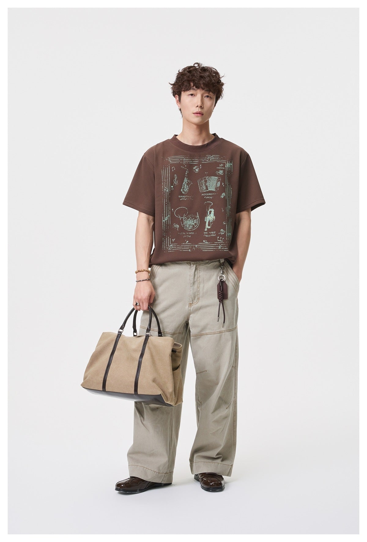 Full-length model wearing a brown graphic T-shirt with a pale musical instrument illustration.
